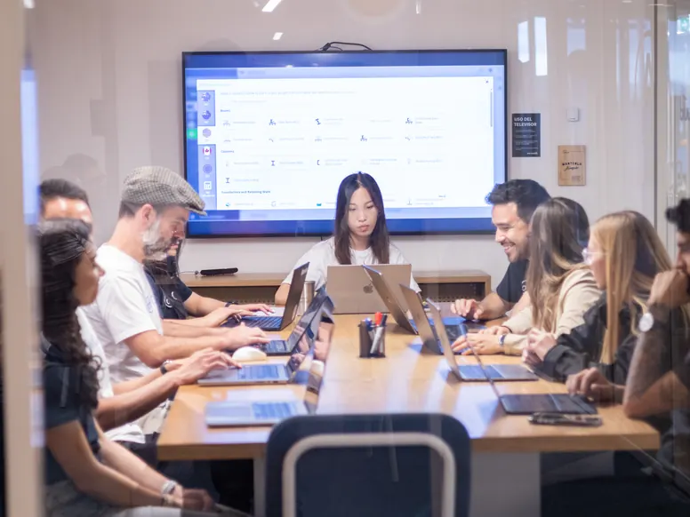 The Bogota team working at a long shared table with the product on the screen behind them