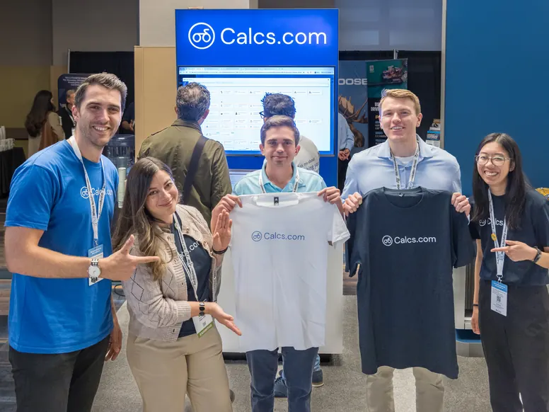 Five Calcs.com team members holding up branded t-shirts at the stand